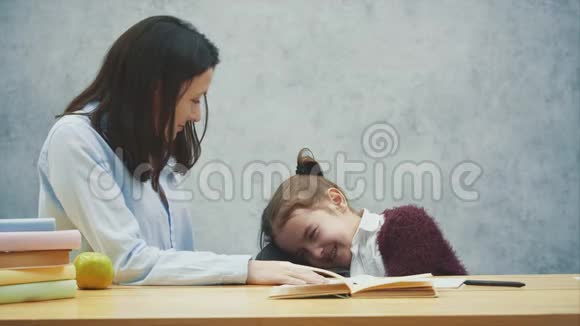 一个灰色背景的女孩坐在桌子旁把头放在椅子的背面在这期间我妈妈微笑着视频的预览图