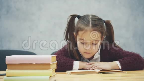 一个女学生坐在灰色背景上在这段时间里小学生仔细阅读这本书勤奋的学生视频的预览图