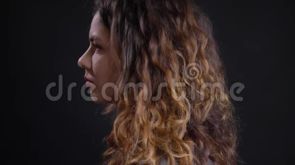 年轻的白种人女性卷曲的棕色头发转过头来看镜头面部表情严肃视频的预览图