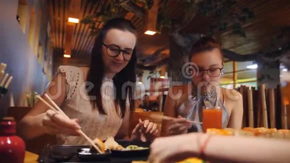 泛亚餐厅的家庭晚餐母女俩用木筷卷吃饭寿司和大套餐视频的预览图