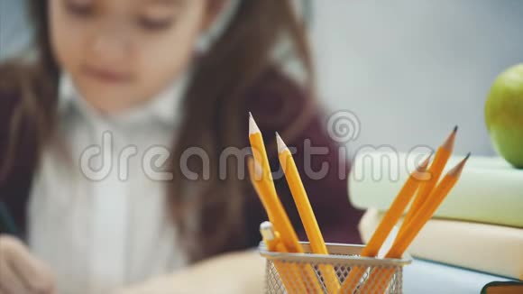 在灰色背景下关闭女学生在这段时间里他坐在桌子旁用铅笔画一幅画视频的预览图
