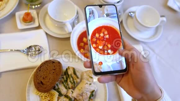 双手使用智能手机用番茄酱和面包片拍摄鸡肉面食的照片视频的预览图