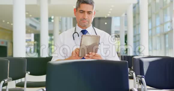 高加索男医生在办公室大厅里拿着数码平板电脑视频的预览图