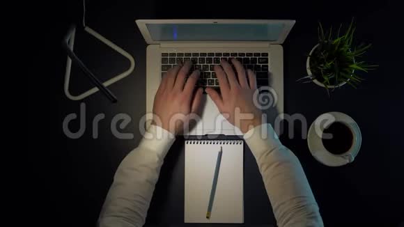 晚上穿着白色衬衫的男性商人坐在桌子旁用笔记本电脑工作喝咖啡视频的预览图