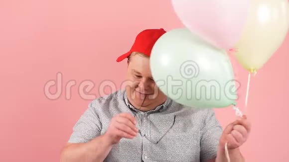 穿着红色棒球帽穿着格子裤摆着气球动作缓慢的成年男子视频的预览图