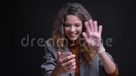 一幅美丽的年轻女性的特写照片她在手机上打了一个视频电话挥手打招呼视频的预览图