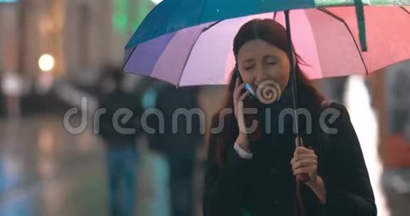带着雨伞的年轻女子在打电话视频的预览图