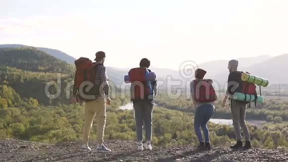 一群带着旅游背包和服装的嬉皮士在高山的背景下跳跃和欢乐视频的预览图