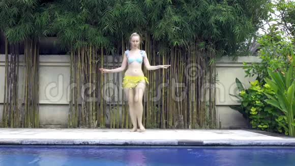 年轻苗条的女人在热带度假胜地的游泳池附近跳舞慢动作视频的预览图