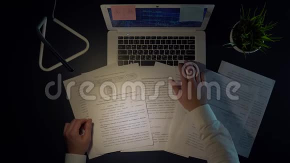 咄咄逼人的男人扔文件晚上拿着笔记本电脑坐在桌子旁视频的预览图