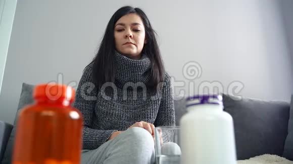 生病的年轻女人用水吃药视频的预览图
