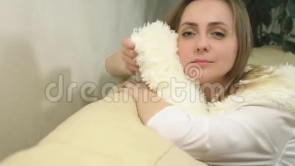 可爱的金发美女的肖像享受白色蓬松围巾的柔软视频的预览图
