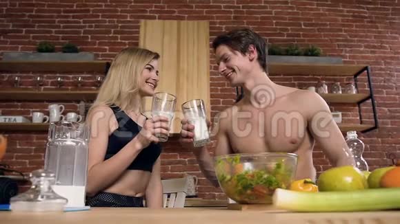 英俊的运动情侣在厨房里喝牛奶视频的预览图