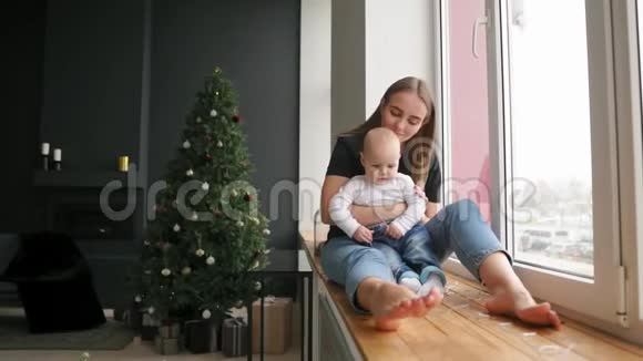 年轻的母亲正牵着儿子手而他正走在装饰着圣诞花环的窗台上快乐视频的预览图