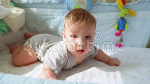 婴儿床上的小婴儿笑着试图爬行快乐的童年幼稚的快乐人生的第一步视频的预览图