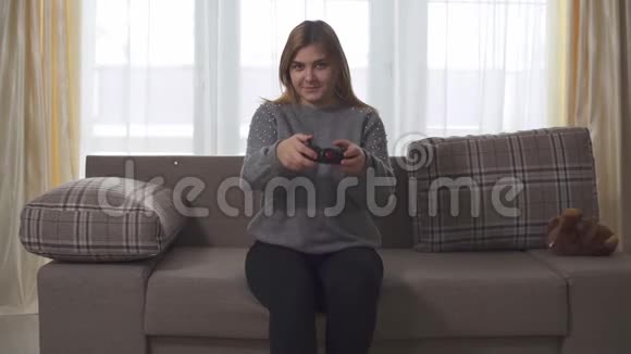 胖女孩在家坐在沙发上玩电子游戏胖女人手里拿着操纵杆多大号女士休闲视频的预览图