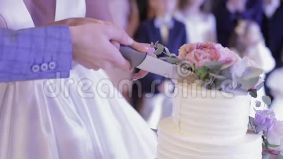 新娘和新郎正在切婚礼蛋糕双手切一块蛋糕视频的预览图