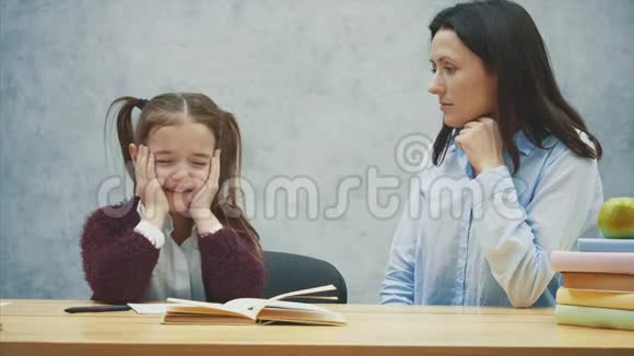 一个灰色背景的女孩坐在桌子旁哭泣在这期间我母亲正在和她的女儿吵架概念视频的预览图