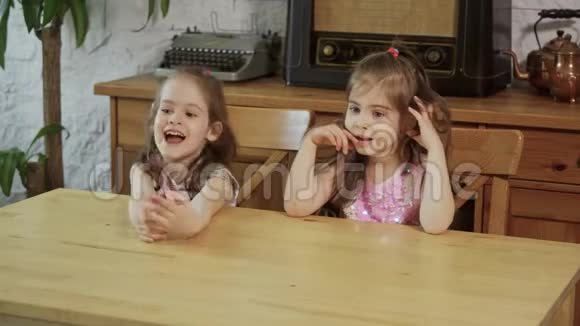 两个小女孩笑着对着木桌说话视频的预览图