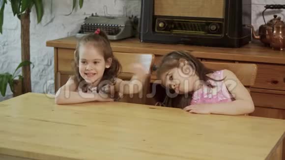 两个小女孩笑着对着木桌说话视频的预览图