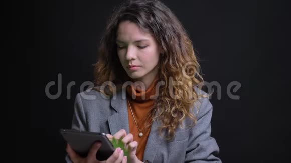 在平板电脑上输入漂亮的深色头发的女性的宏观特写照片并将绿色屏幕显示在相机上微笑视频的预览图