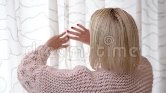 一个成年的金发女人早上从窗外偷看视频的预览图