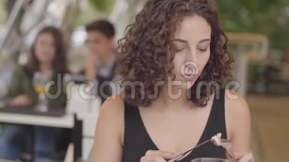 年轻漂亮的卷发女人在街头咖啡馆里吃着美味的肉菜和土豆享受甜点放松的女孩视频的预览图
