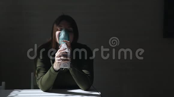 使用雾化器和吸入器进行治疗年轻女子坐在桌子旁用面罩在黑暗中吸入吸入器视频的预览图