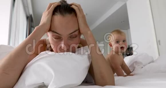 疲惫的母亲躺在婴儿身边的床上视频的预览图