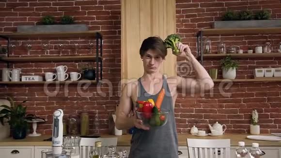 有魅力的素食男孩一只手拿西兰花另一只手拿蔬菜视频的预览图