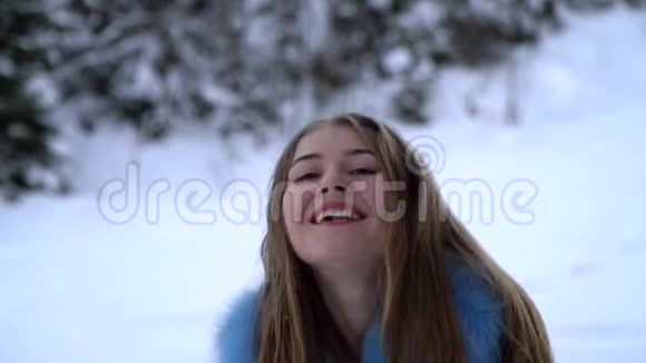 年轻漂亮的女孩走在白雪皑皑的冬林里她既快乐又开朗女孩把雪洒在头上视频的预览图