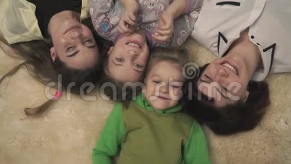 四个人幸福家庭的画像躺在地板上蓬松的地毯上微笑着有趣的家庭假日视频的预览图