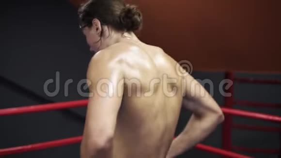 疲惫的赤膊男子靠在拳击绳上在拳击后放松时呼吸沉重的慢动作镜头视频的预览图