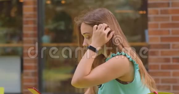 年轻美丽的白种人女性使用手机坐在户外咖啡馆的特写照片视频的预览图