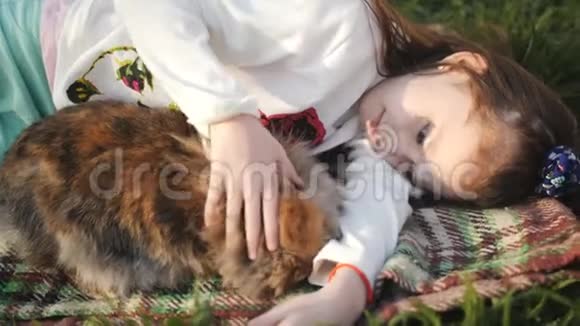 小女孩躺在绿草上拥抱一只棕色的兔子小女孩和棕色兔子躺在绿色的草坪上还有一只视频的预览图