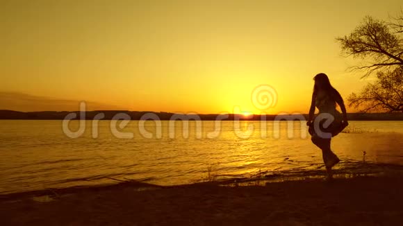 年轻的自由女孩在海边夕阳红下翩翩起舞晚上海滩上跳的快乐女人视频的预览图