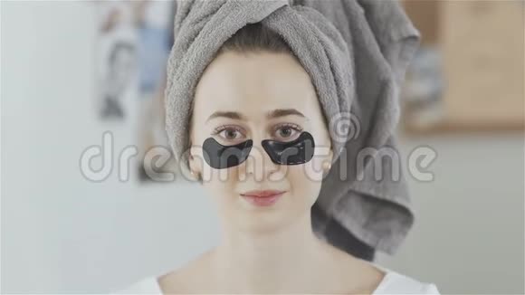 头上戴毛巾的女人摘下一片胶原蛋白水解面膜视频的预览图