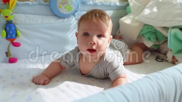 婴儿床上的小婴儿笑着试图爬行快乐的童年幼稚的快乐人生的第一步视频的预览图