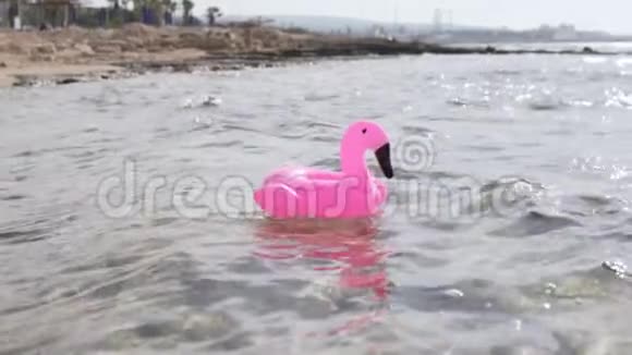充气的粉红色火烈鸟圆圈漂浮在海里视频的预览图