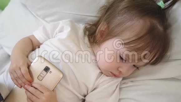 小婴儿躺在床上手里拿着电话睡着了视频的预览图