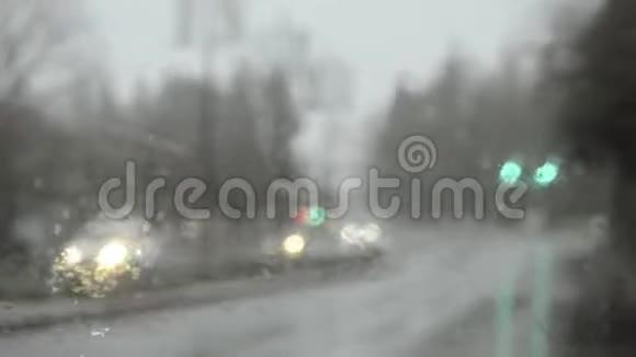 在大雨中驾驶通过黄色交通灯浅焦通过玻璃视频的预览图
