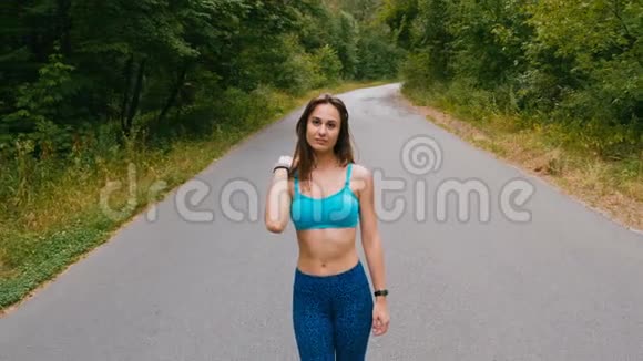 运动青年妇女在森林里的路上行走户外健身用定心丸射击视频的预览图