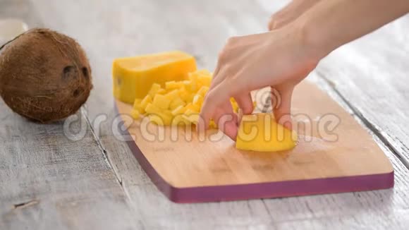 女厨师她的手在木切割板上切芒果夏季健康纯素水果沙拉绿色背景视频的预览图