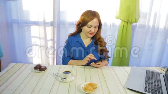 一个棕色头发的女人在一张桌子上的咖啡馆里工作拿着一块药片喝咖啡视频的预览图