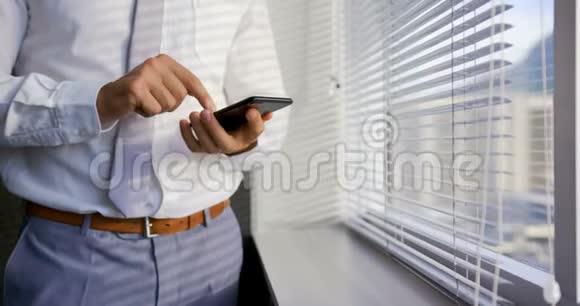 中段白种人年轻男性高管使用手机靠近窗口在现代办公室4k视频的预览图