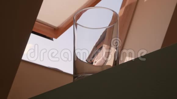 黄色的柠檬水倒在玻璃杯里慢动作背景上阁楼的开着的窗户视频的预览图