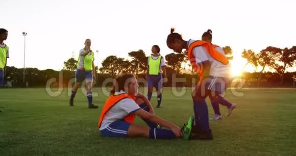 女足球运动员帮助队友站在足球场上4k视频的预览图