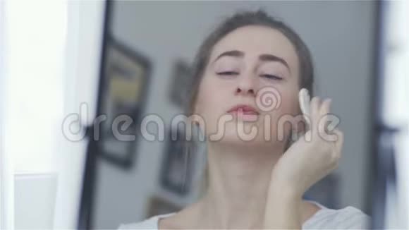 镜子里的倒影女人用棉垫清洁她的脸视频的预览图
