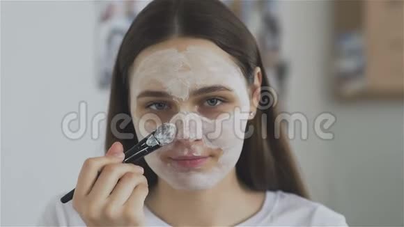 女人用刷子在房间里敷化妆品面膜看看相机视频的预览图