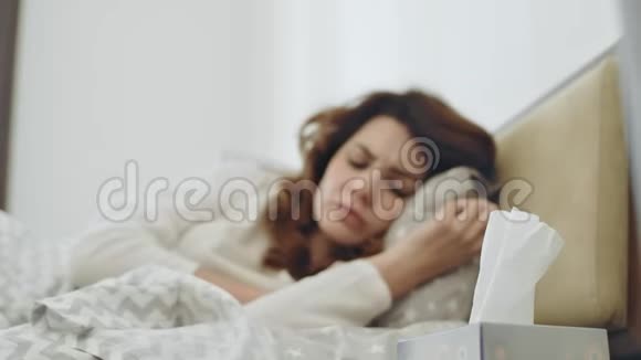 生病的女人在卧室里感觉不好生病的女性在床上打喷嚏视频的预览图